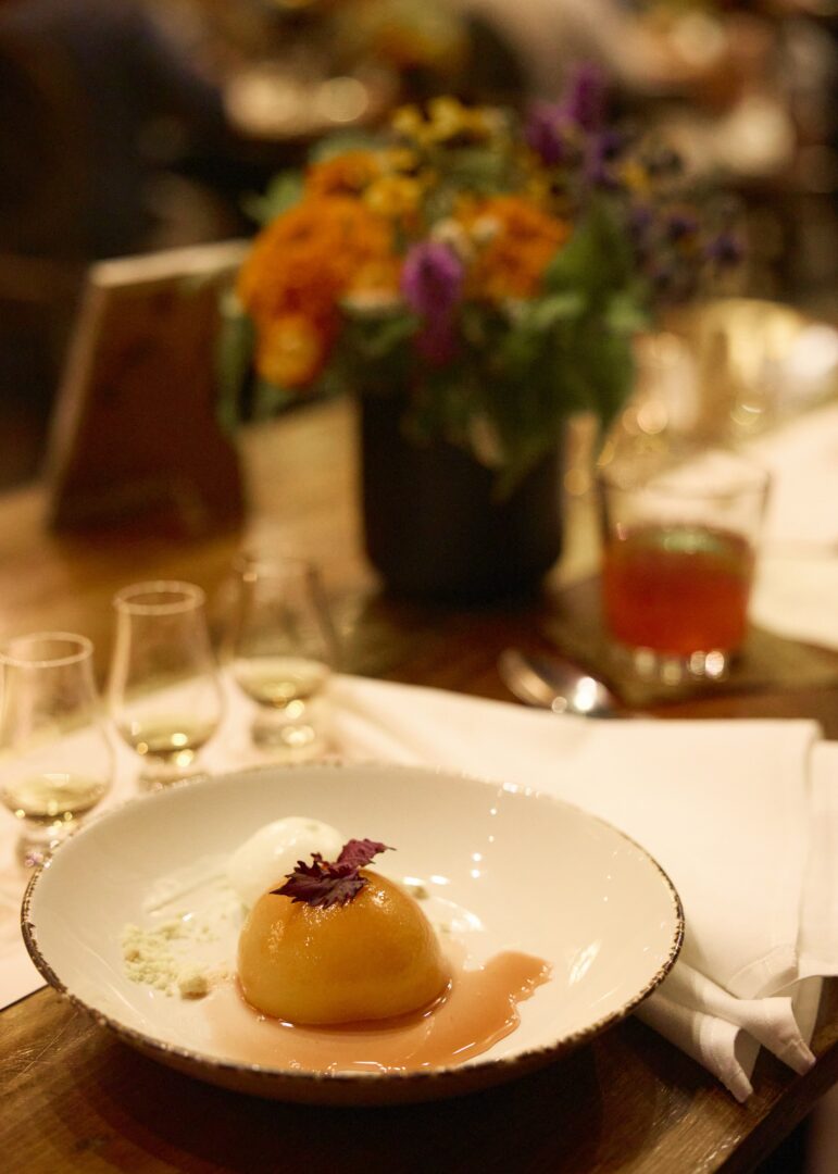 A rice like dessert on a plate with flowers on the table.