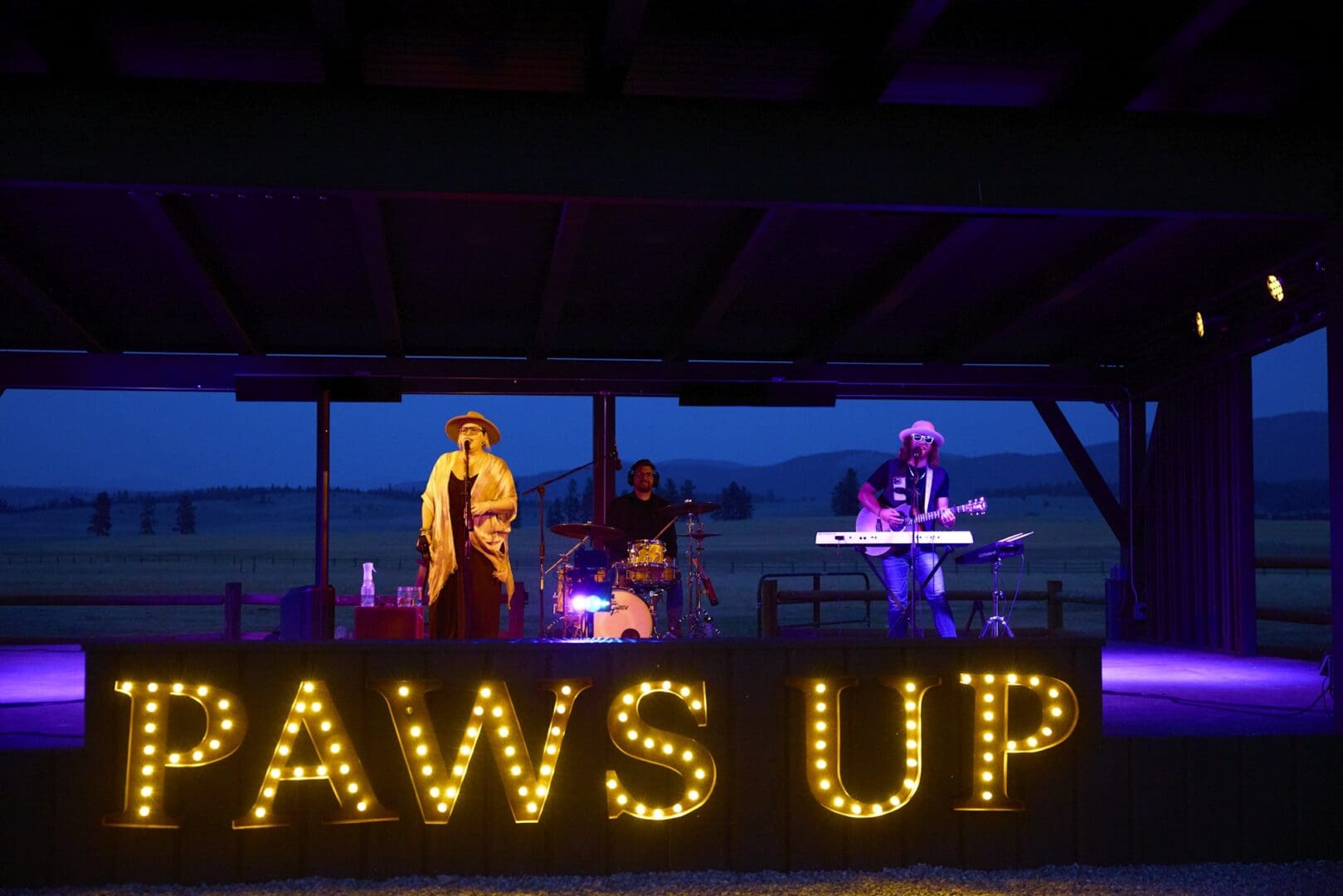 Woman singing on a stage with a "Paws Up" sign below her.