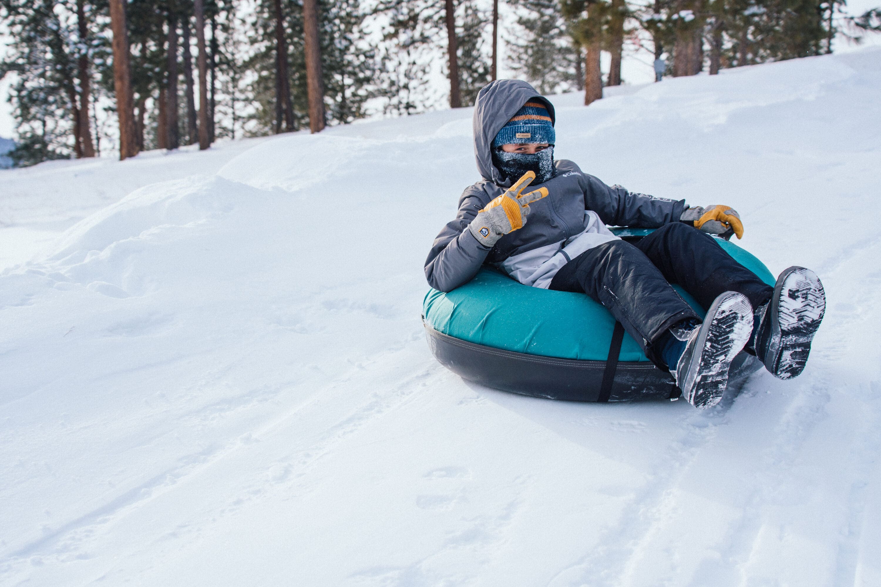 Kid tubing down a snow hill.