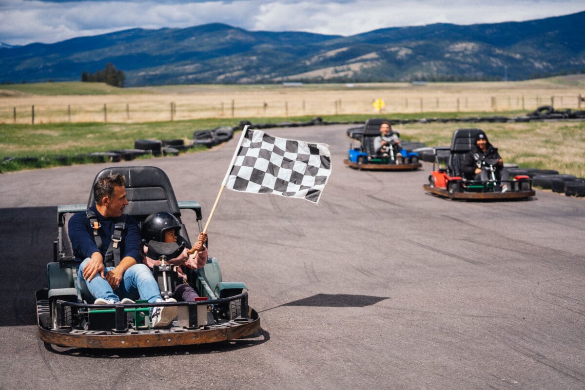 Family racing on a go-kart track outside with a racing flag.