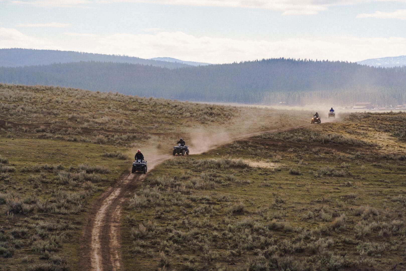Three individuals riding ATV's on a dirt trail.