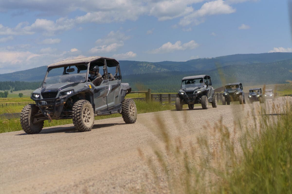 Individuals riding ATV's on a dirt road.