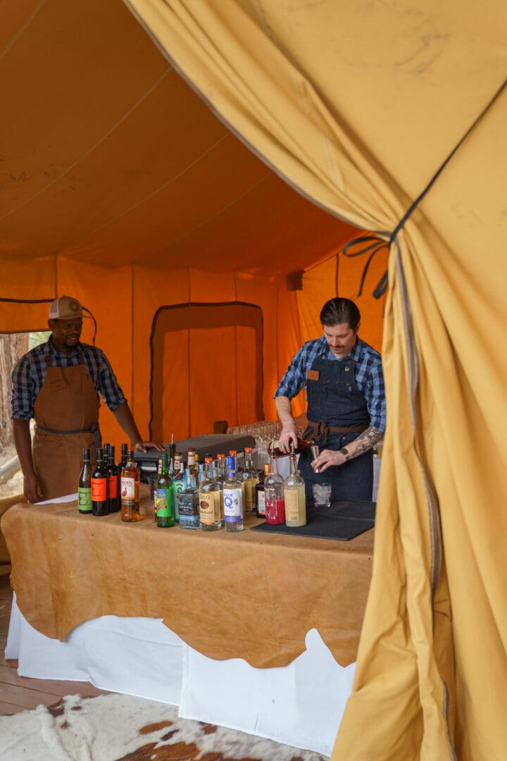 Two bartenders working under a tent.