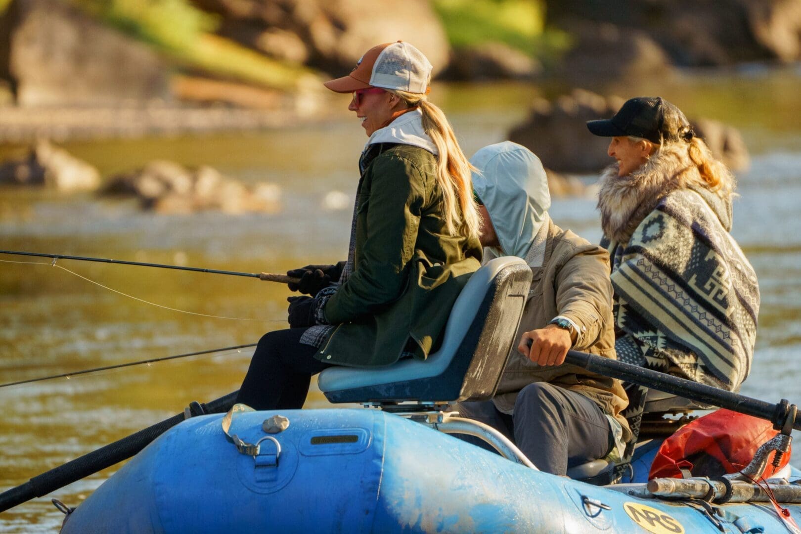 Women sitting on a boat fly fishing on a river.