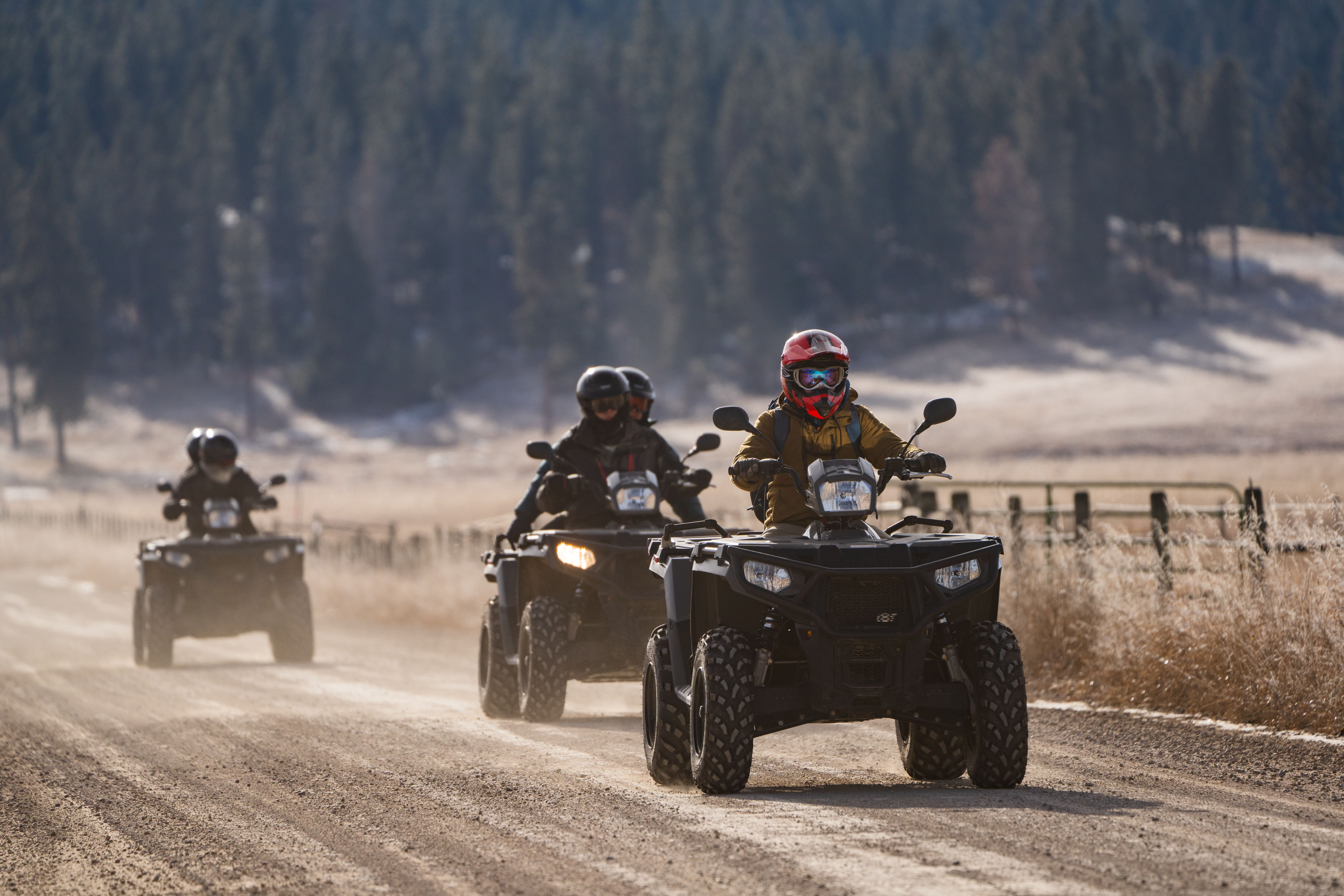 Wide view of people driving ATVs on a dirt trail during a backcountry tour.