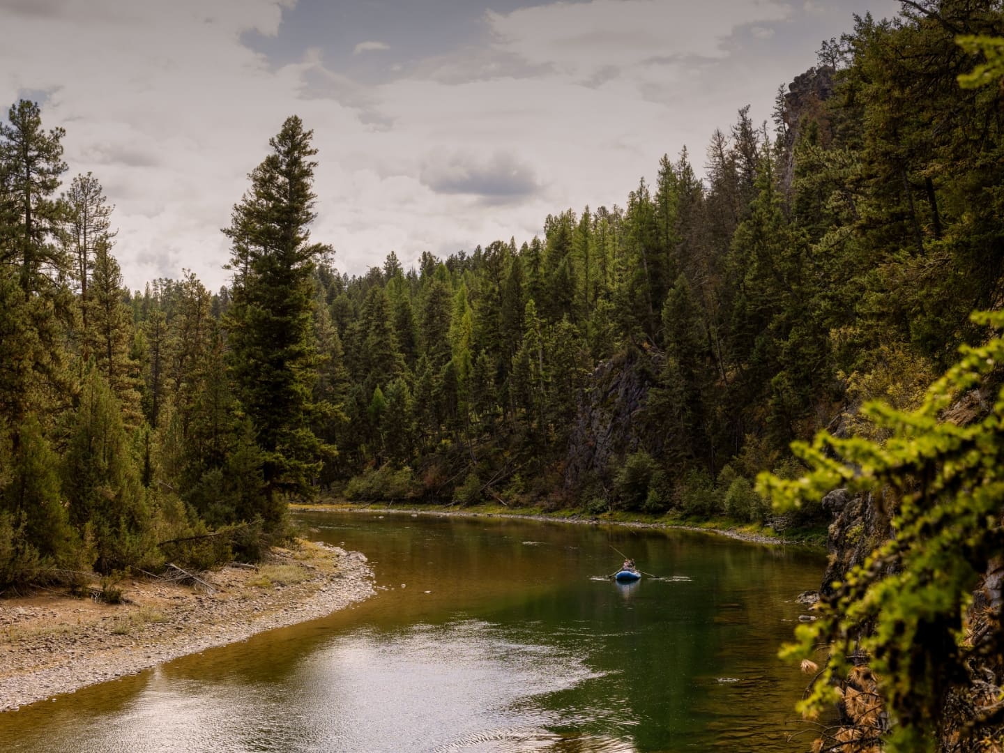 Person kayaking in an expansive mountain river