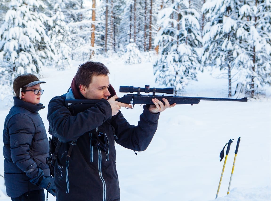 man shooting rifle in snowy forest for biathlon