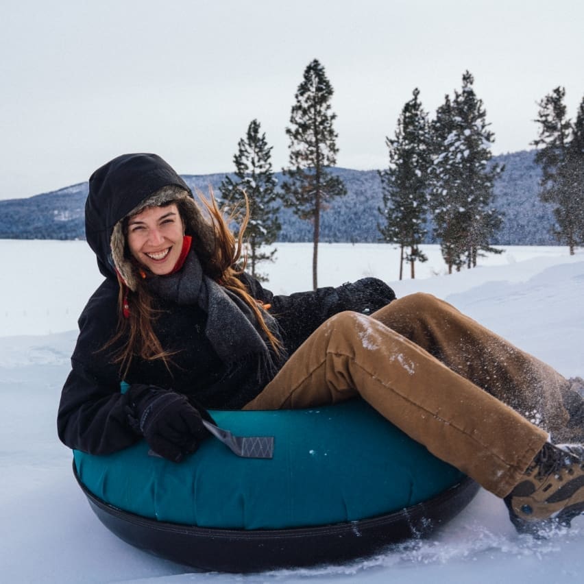 Smiling woman tubing down a snowy hill on Blast Mountain at Paws Up