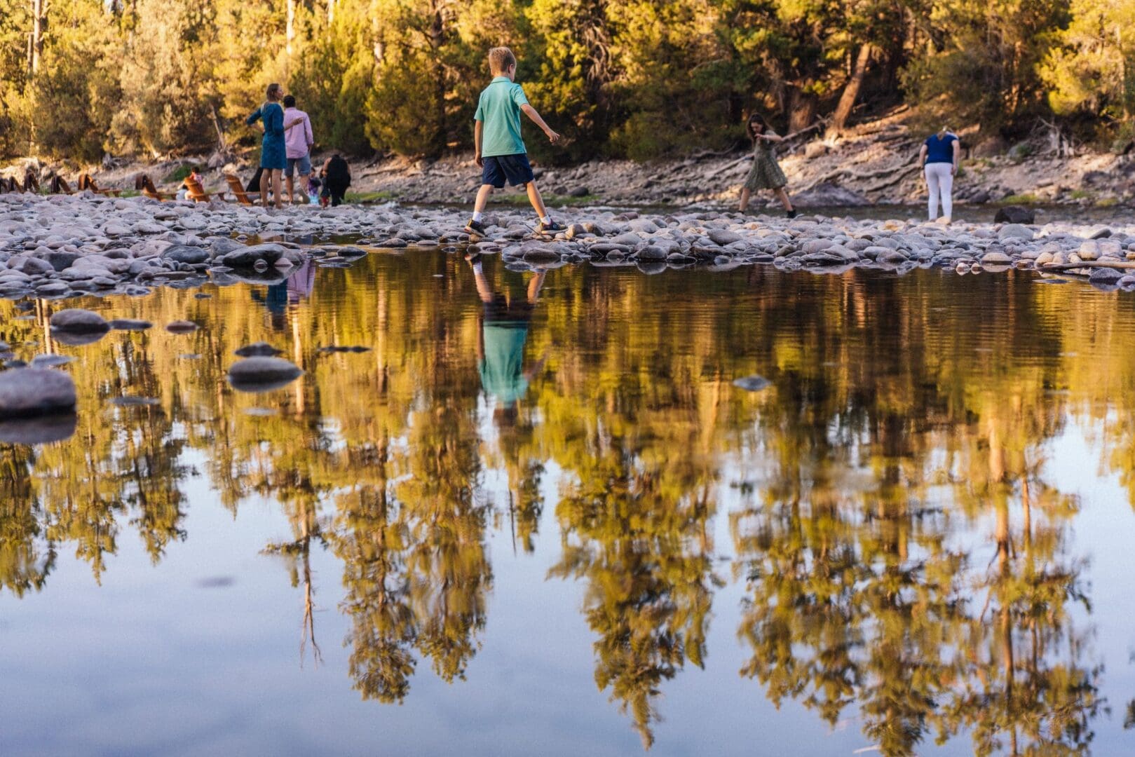 Group of kids walking across the rocks in the Blackfoot River