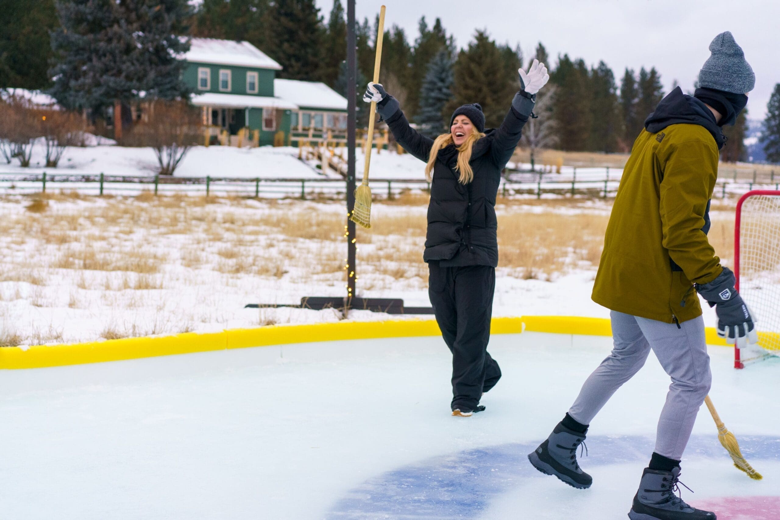 Woman celebrating a goal in broom hockey on an ice rink