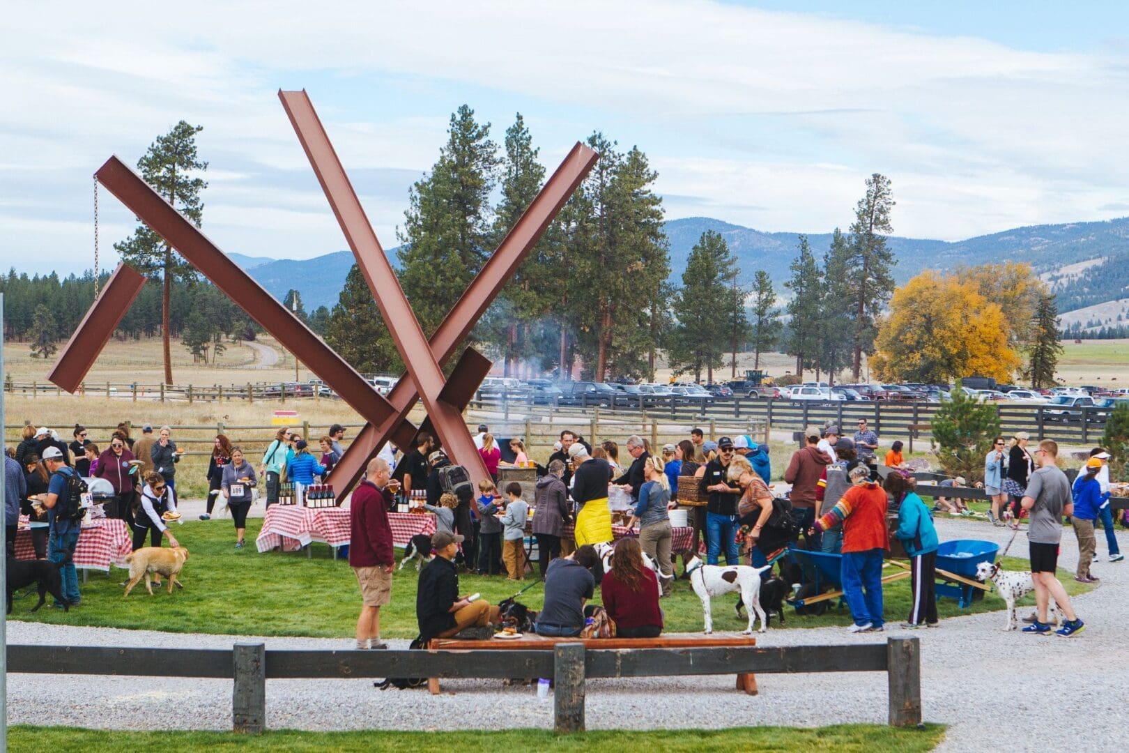Gathering of people and their dogs at the Paws Up Annual Canine Classic, clustered on the resort grounds surrounded by Montana mountains