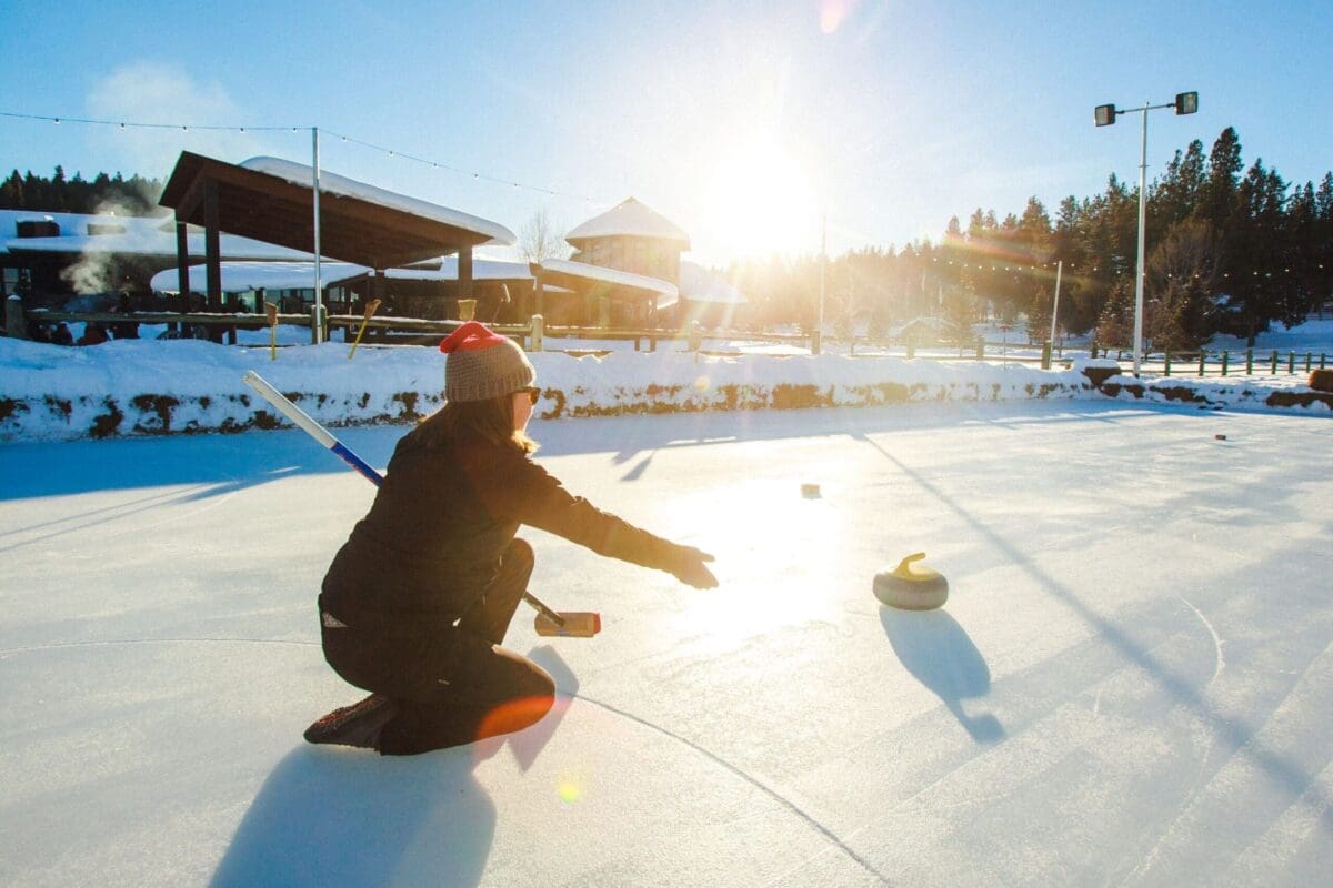 Woman curling on an ice rink at Paws Up