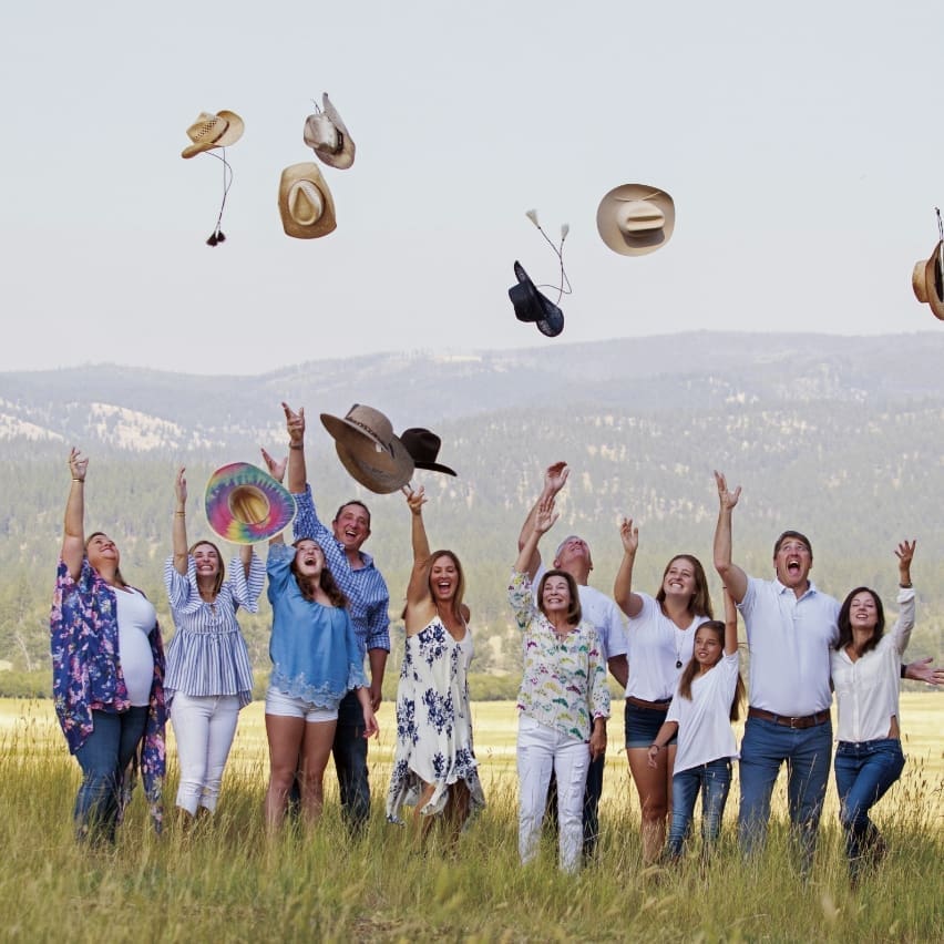 Multi-generational family throwing their cowboy hats in the air