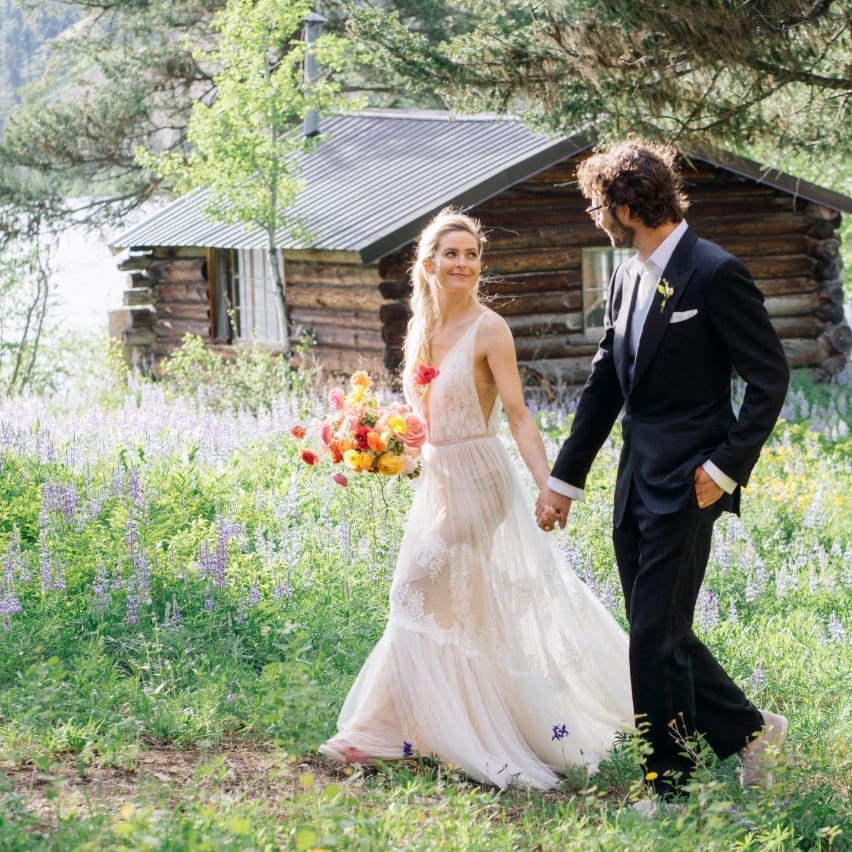 Couple happily walking through a field on their wedding day
