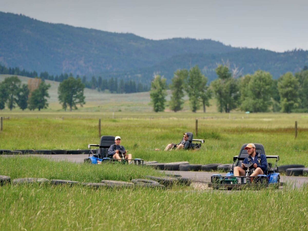 Group of people racing around the go-kart track in a mountainous field