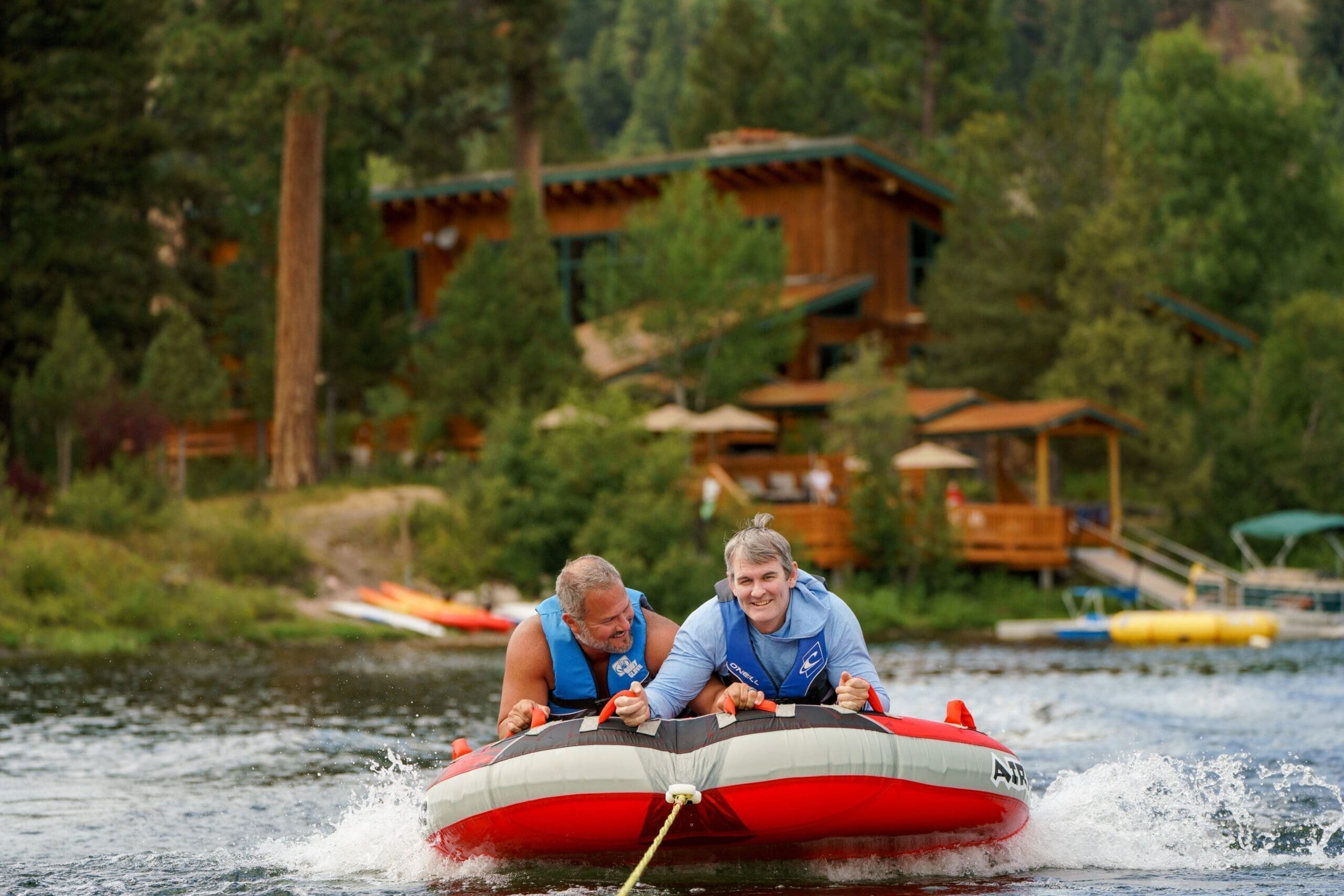 Two men tubing behind a boat in a lake at the Island Lodge