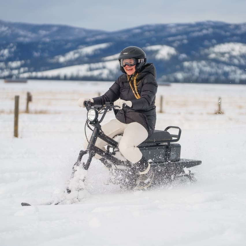 Eager driver riding a moonbike (electric snowbike) through the winter mountain snow
