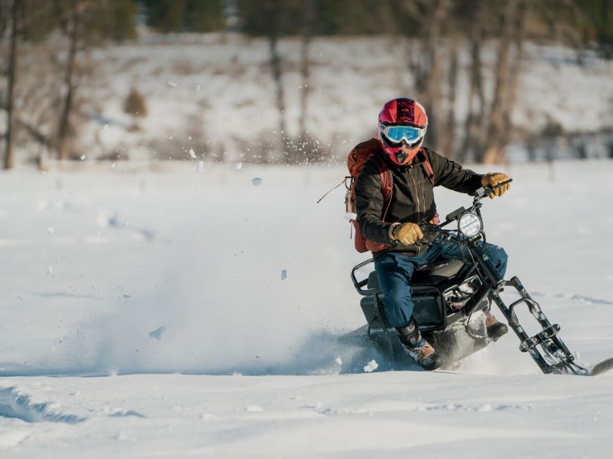 Person quickly riding a moonbike (electric snowbike) through the winter snow