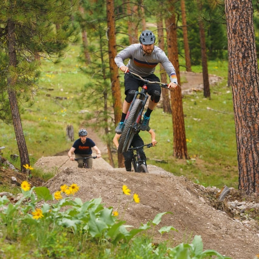 Mountain biker getting some air off of a dirt jump in the forest