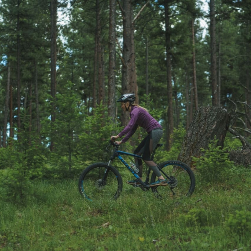 woman biking on a mountain bike through the green forest