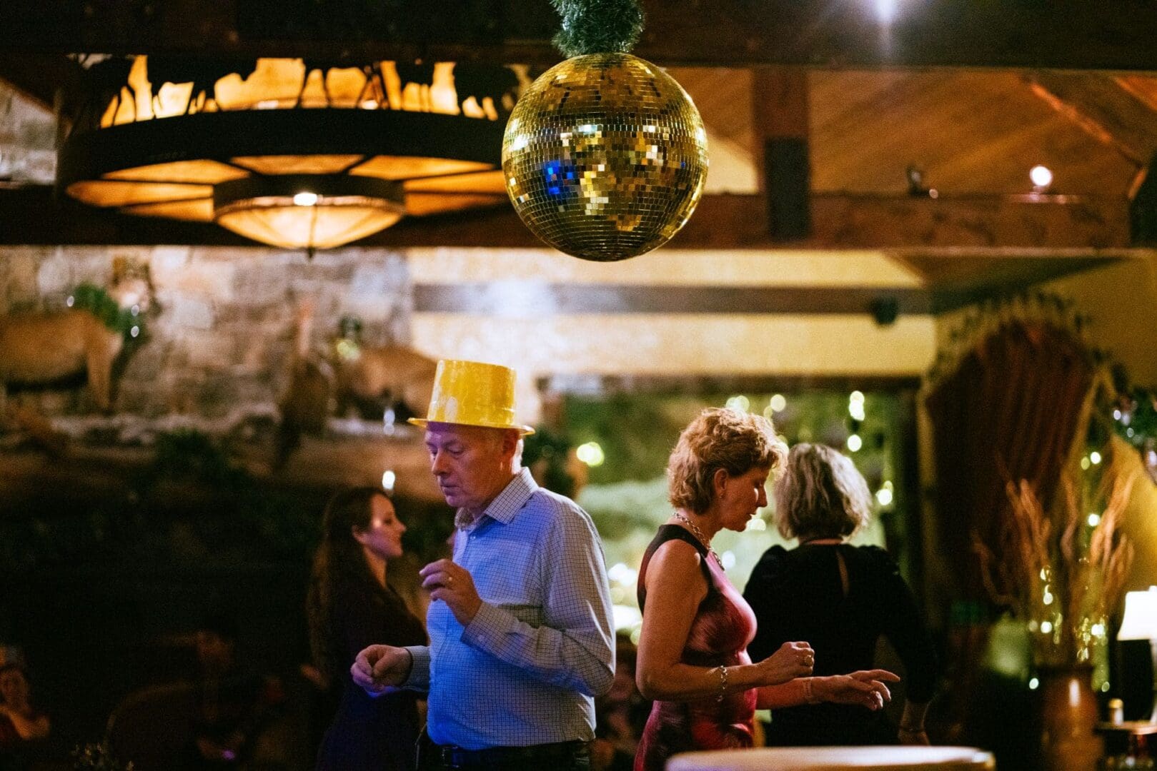 Group of people at a New Year's Party in Pomp restaurant with a golden disco ball hanging from the ceiling