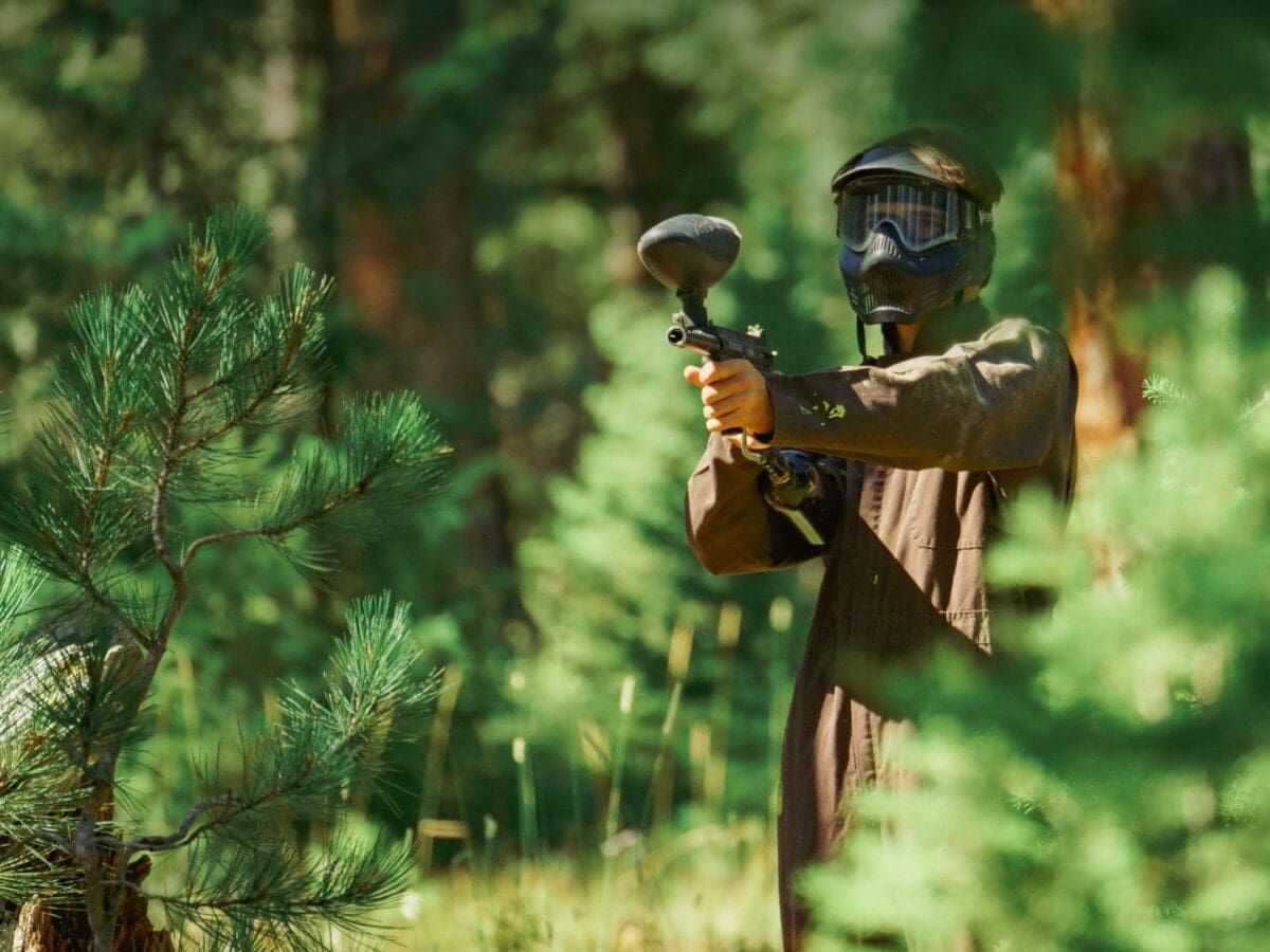 Person aiming a paintball gun in the forest