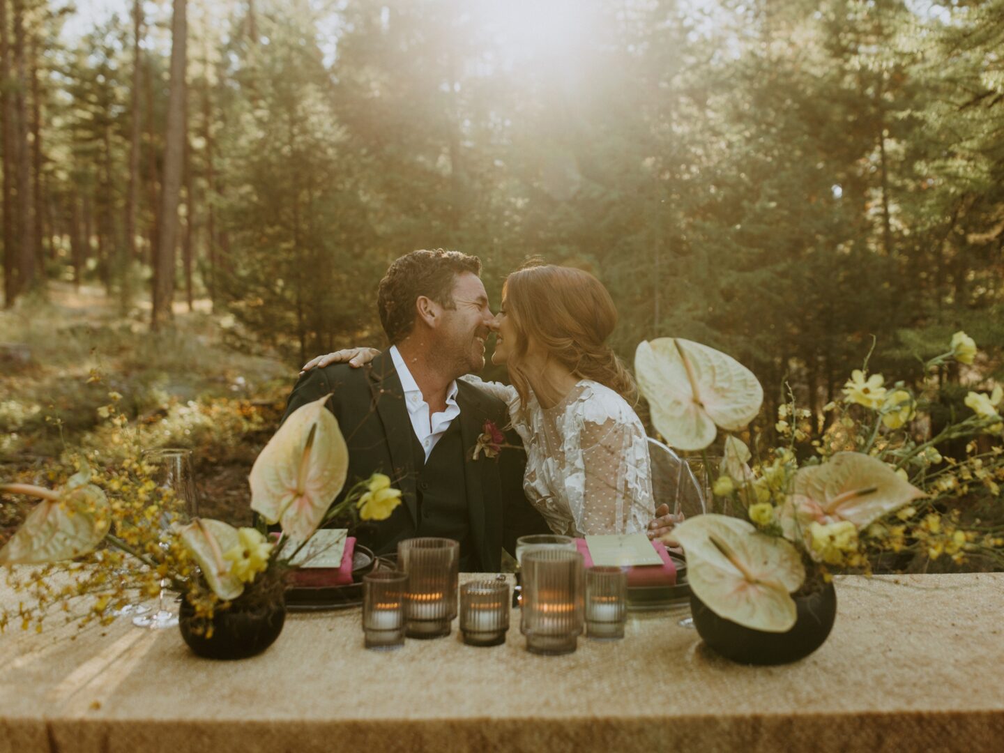 Bride and groom sitting at their wedding reception table outside.