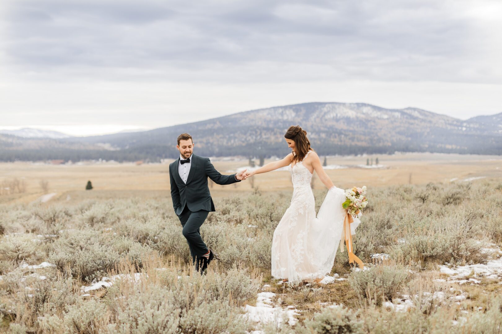 Bride and groom walking outside with mountains behind them.