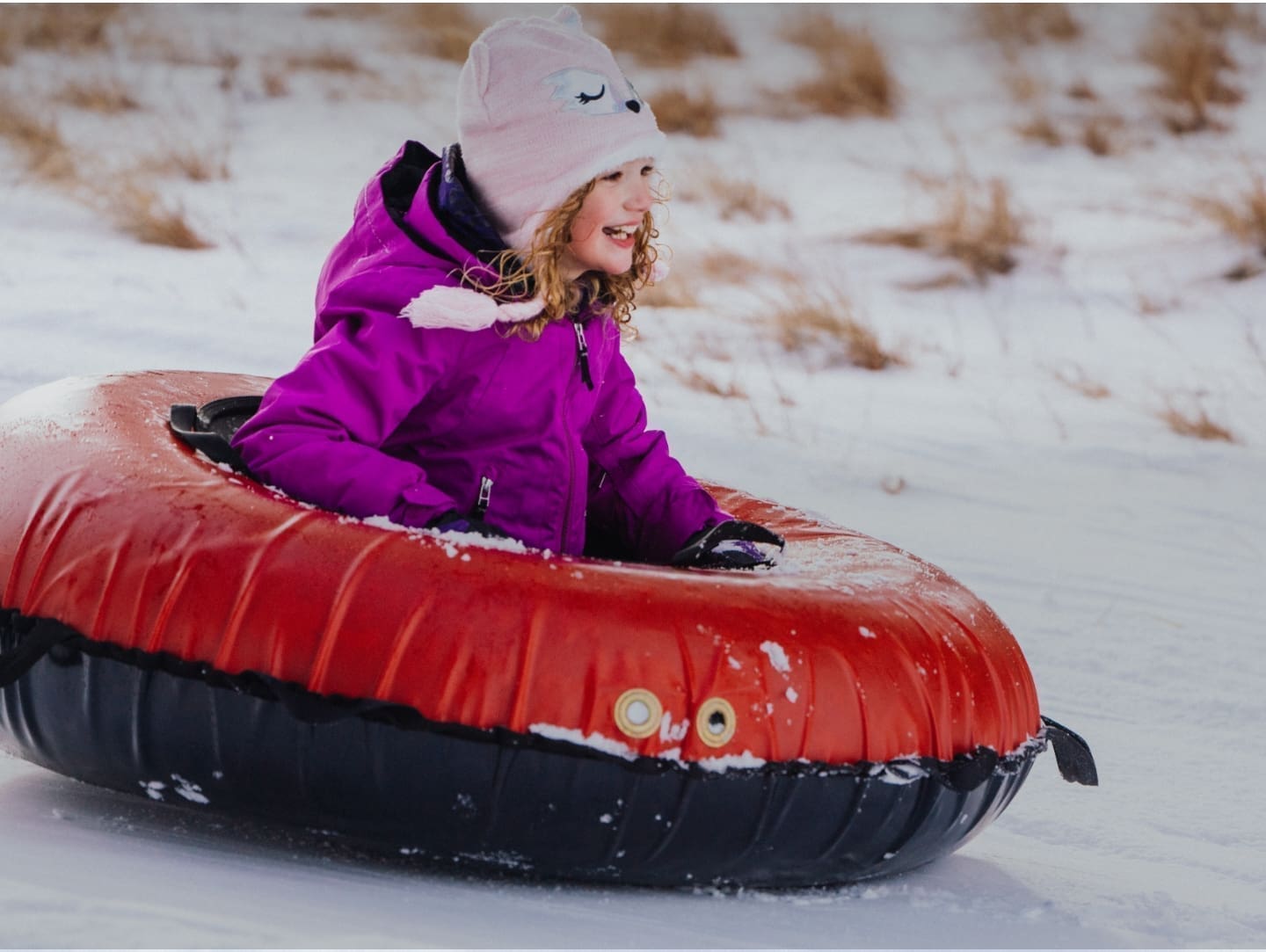 Little girl tubing down a hill in the snow