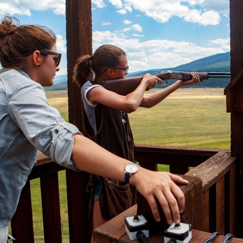 Young girl shooting a rifle guided by an instructor