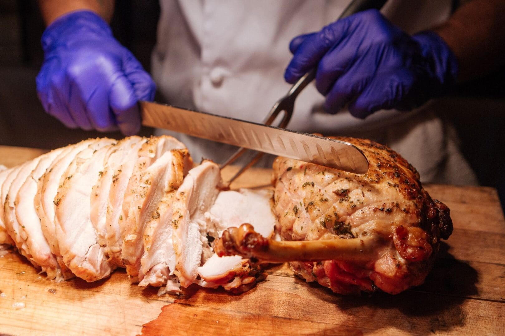 Chef cutting chicken on a wooden cutting board