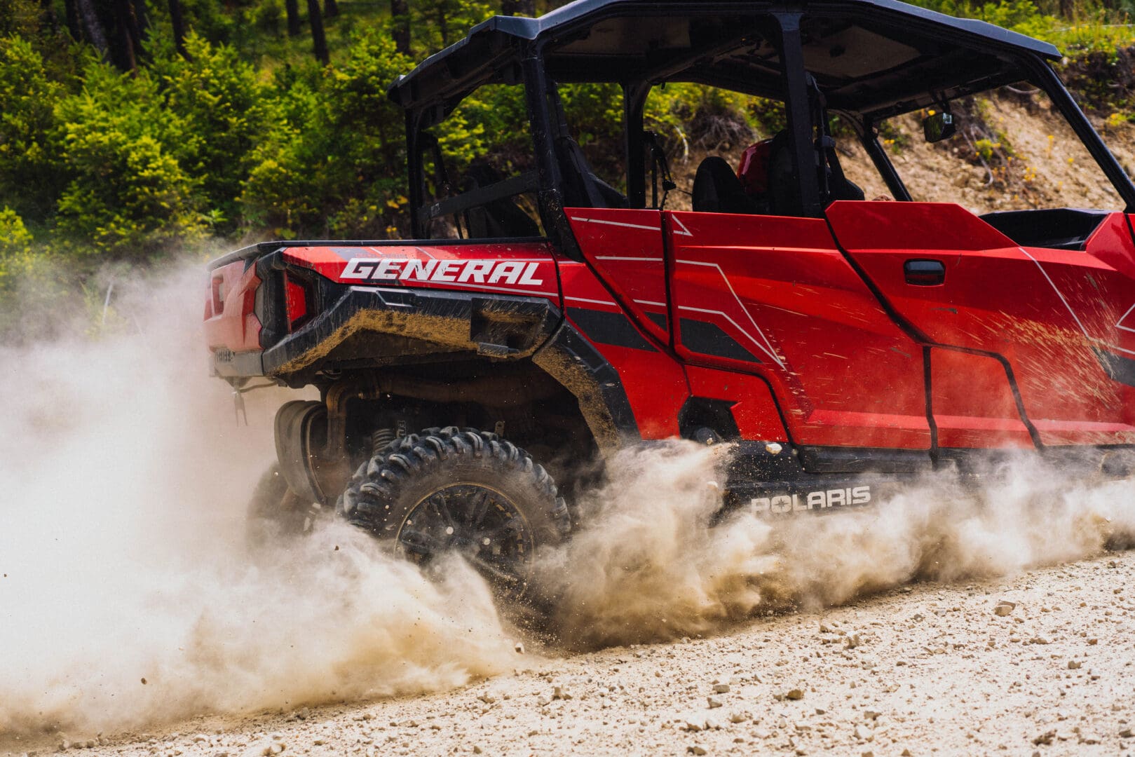 Red UTV driving through dirt.