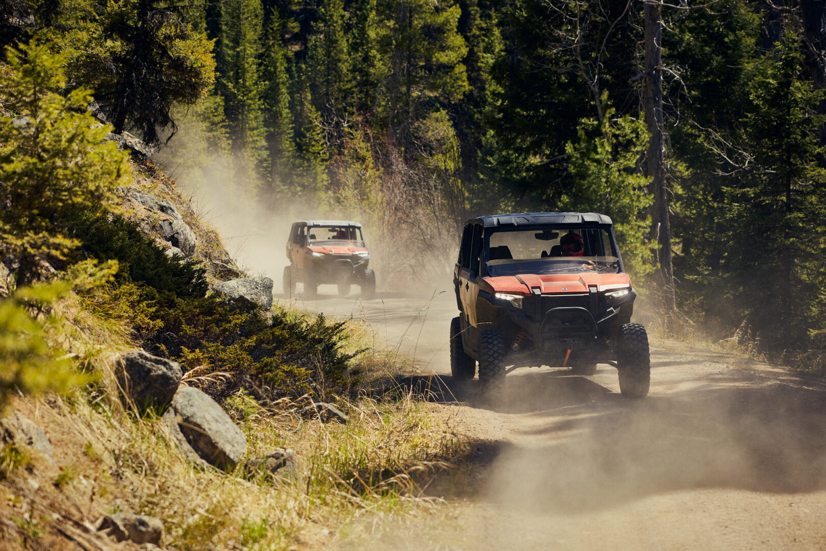 Individuals riding UTV's on a dirt road.