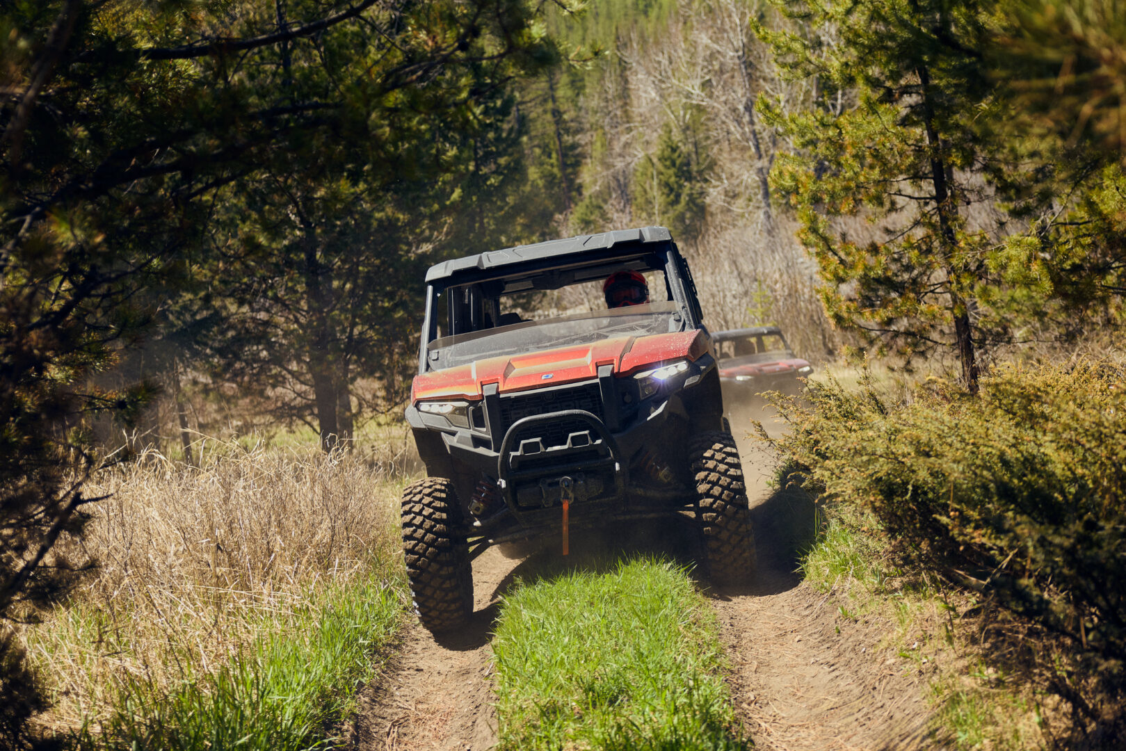 Individual riding UTV's on a dirt road.