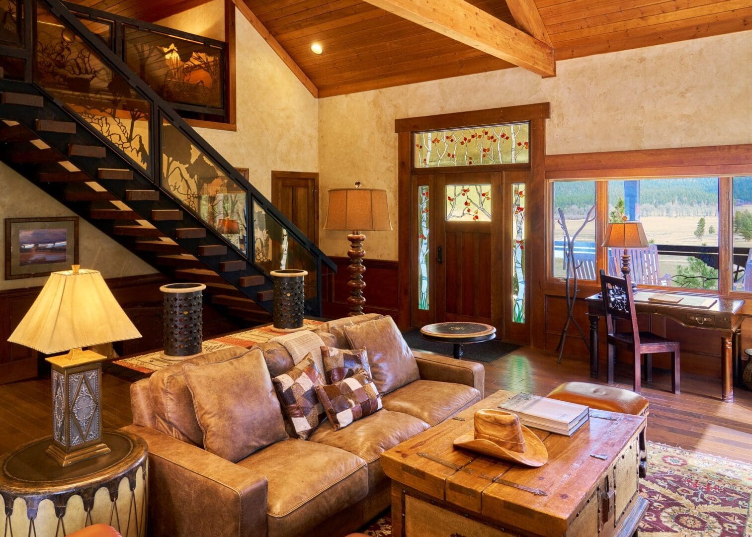 Indoor view of a living room in a Wilderness Estate home, featuring a leather couch, western accents, and a stained-glass front door