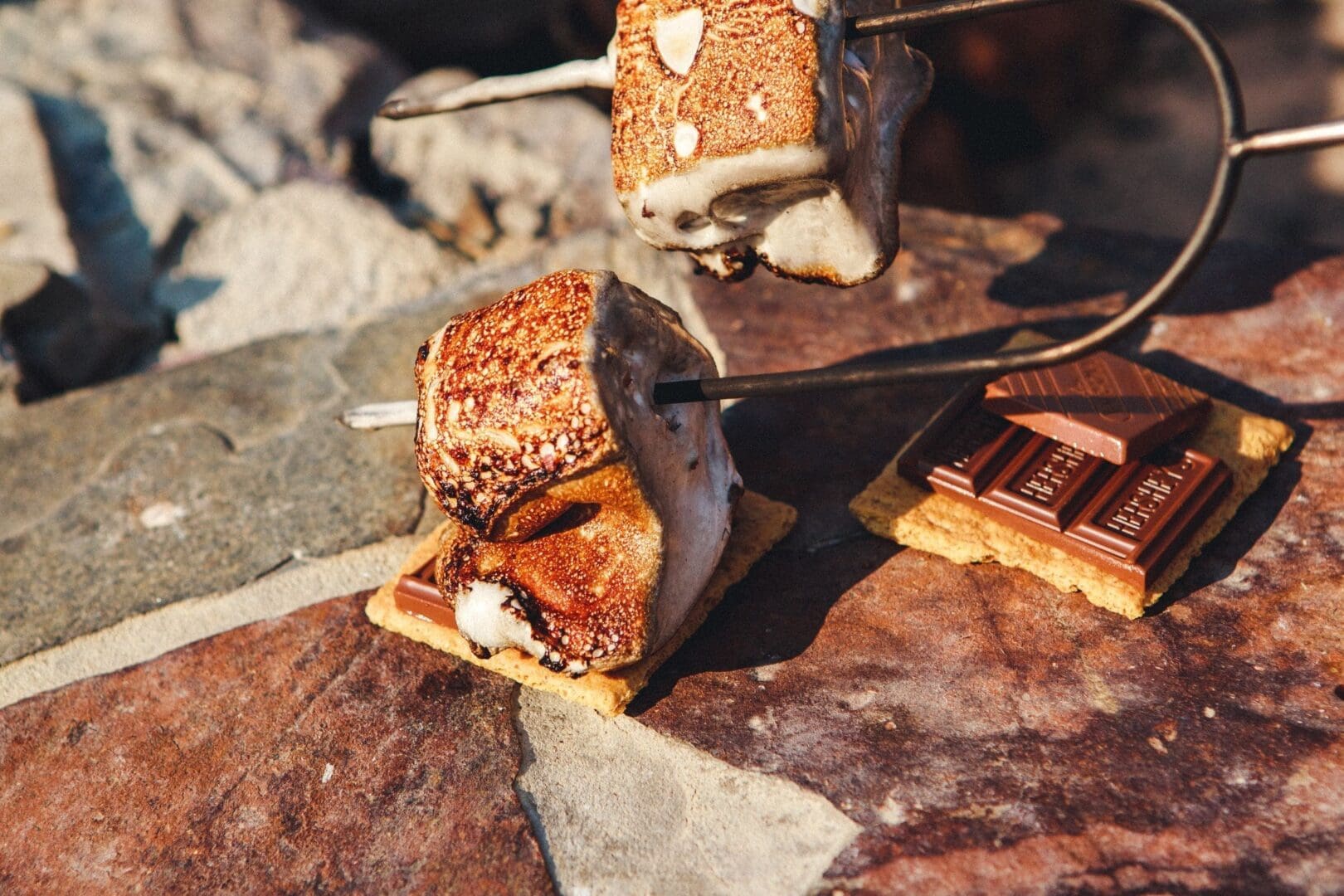 Gooey, golden-brown marshmallow melting onto a graham cracker with chocolate to create the perfect smore