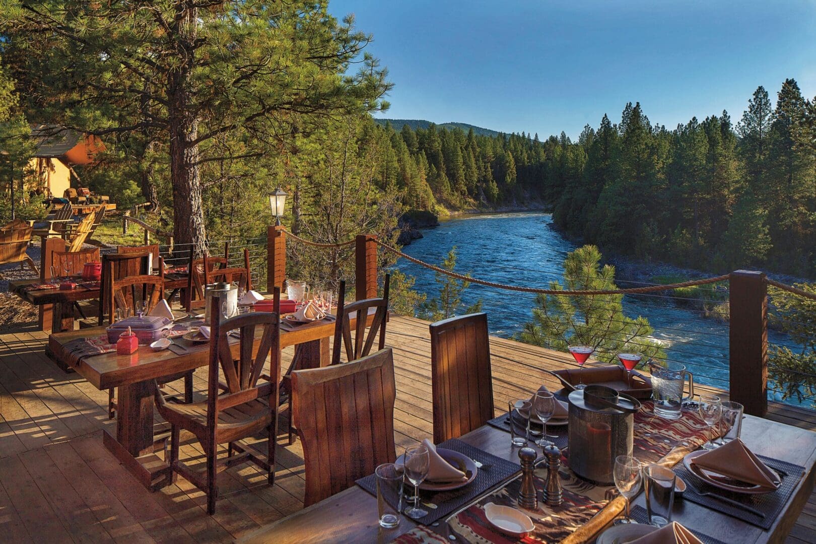 Outside dining deck beside the Blackfoot River with luxury wooden chairs and tables