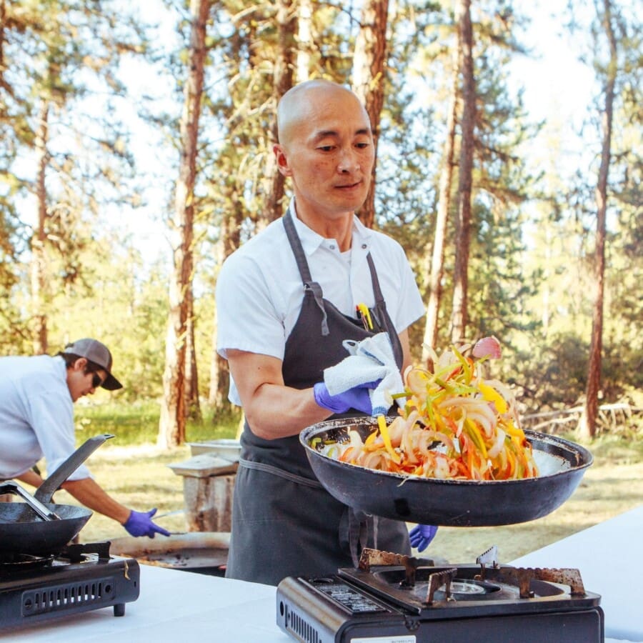 Chef Sunny grilling peppers and onions outside in the forest for the Bounty on the Blackfoot event at Paws Up Montana