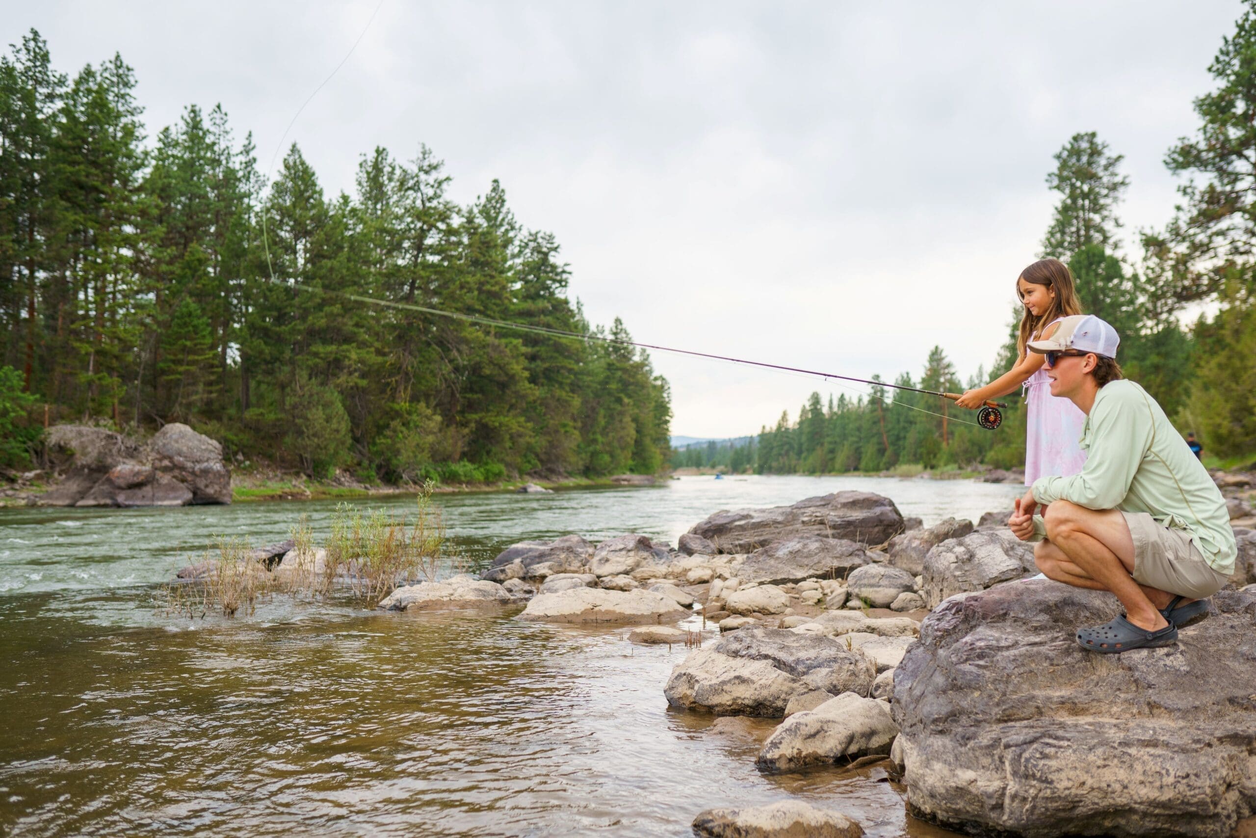 Fly fishing instructor teaching a little girl to fly fish