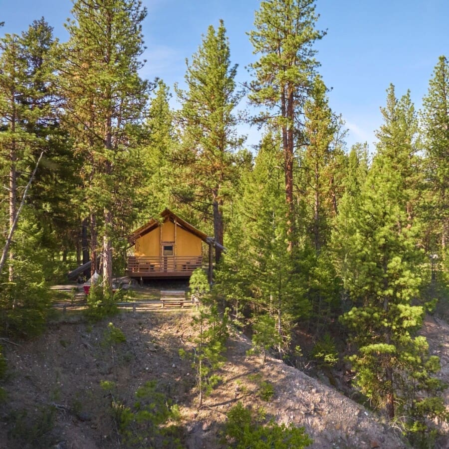 Wide view of a glamping tent on a cliff beside the Blackfoot River