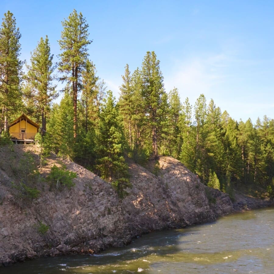 Wide view of a glamping tent on a cliff beside the Blackfoot River