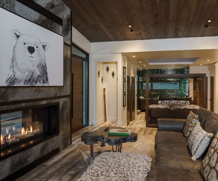 Living room view inside Green Haus at Green O, showing the fireplace, leather couch, and bed from afar