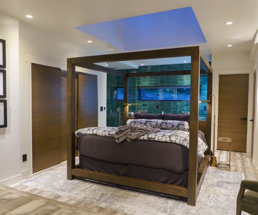 View of the king bed inside Green Haus at Green O, featuring a king-sized wooden bed frame and dark gray comforter