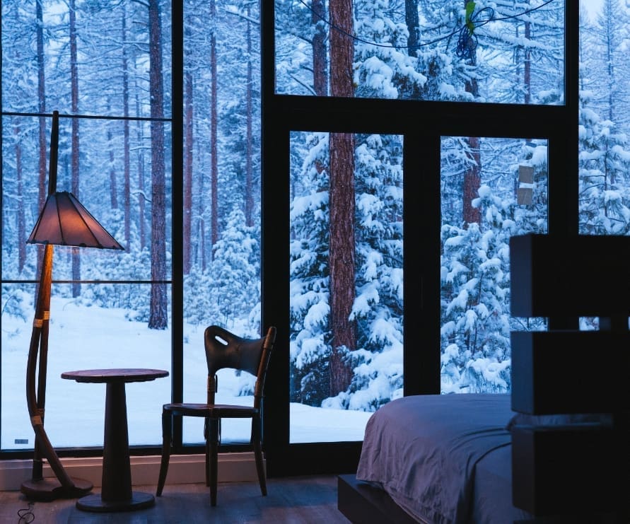 Bedroom view in Light Haus at Green O, showing the snowy forest outside the windowed wall