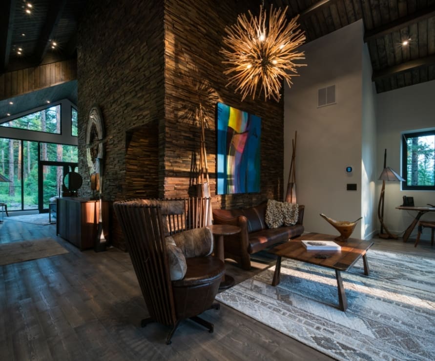 Living room in Light Haus in the Green O at Paws Up, showing a leather chair, wooden coffee table, gray area rug, and stone wall