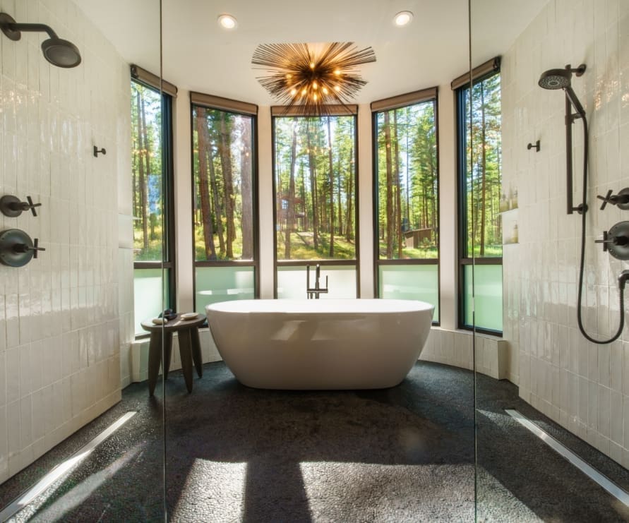 Inside view of the Round Haus bathroom at Green O, a white-tiled double shower and bathtub under a chandelier