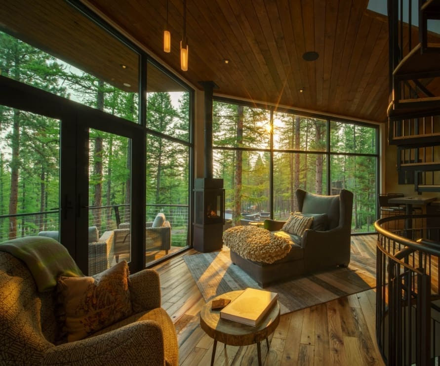 Inside view of the Tree Haus living room at golden hour, showing a leather chair and outdoor deck through the windows