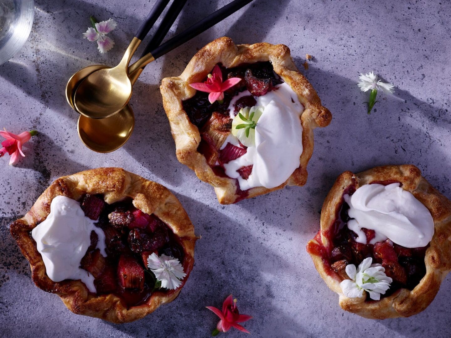 Summer berry tart desserts with whipped cream and flower garnish