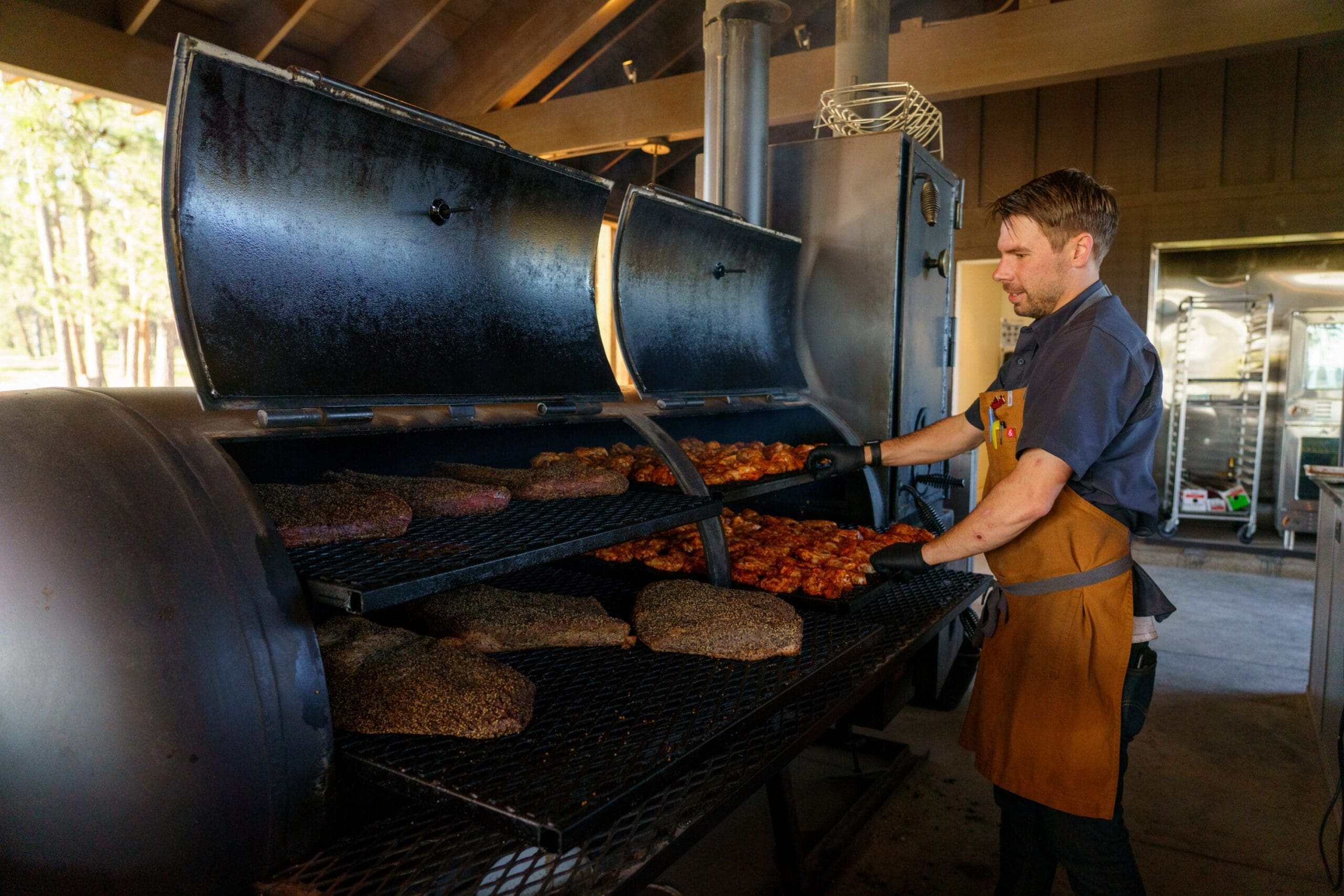 Chef cooking chicken and beef in a large grill at Shed restaurant at Paws Up