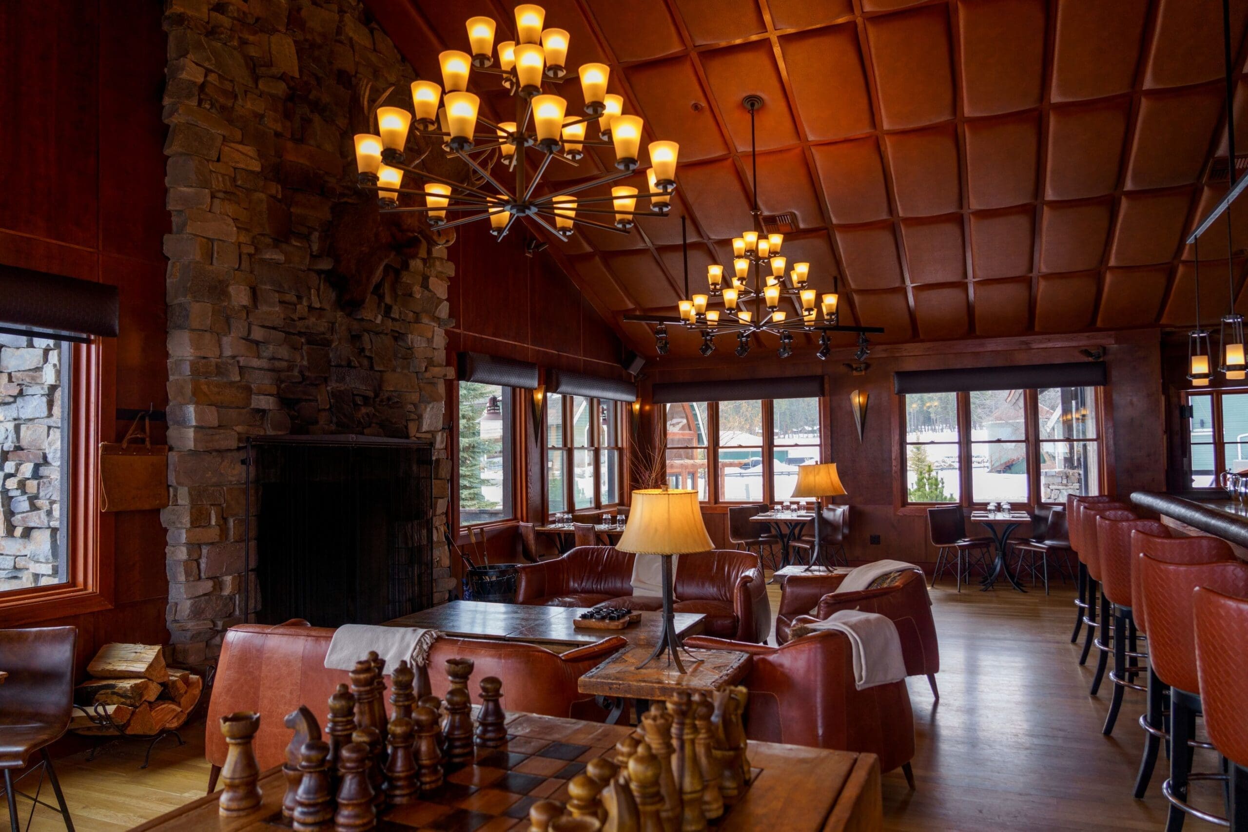 Indoor view of the bar Tank at Paws Up Montana, a modern twist on a leather western look, with dark leather seating and a stone fireplace